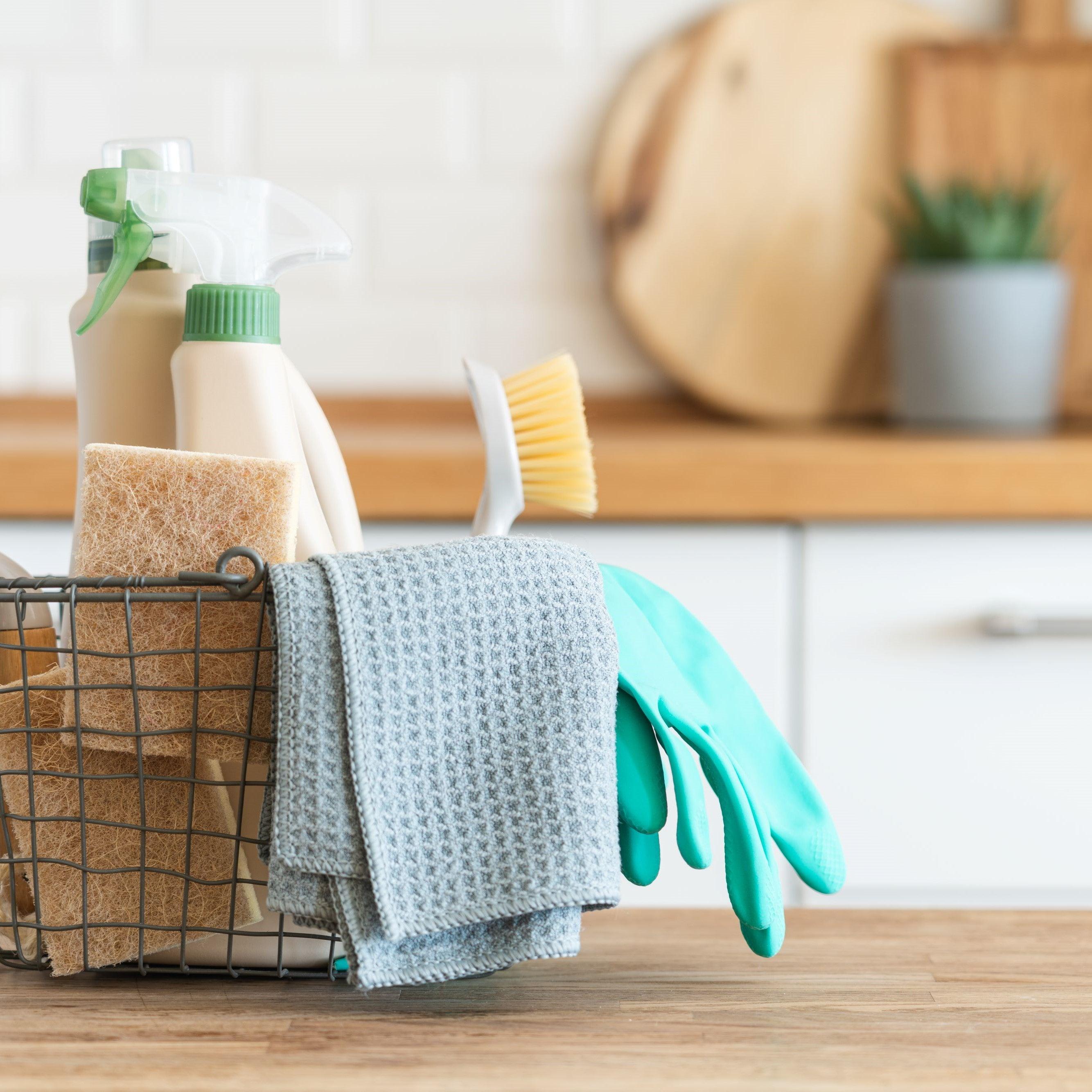 A basket with brushes rags natural sponges and cleaning products