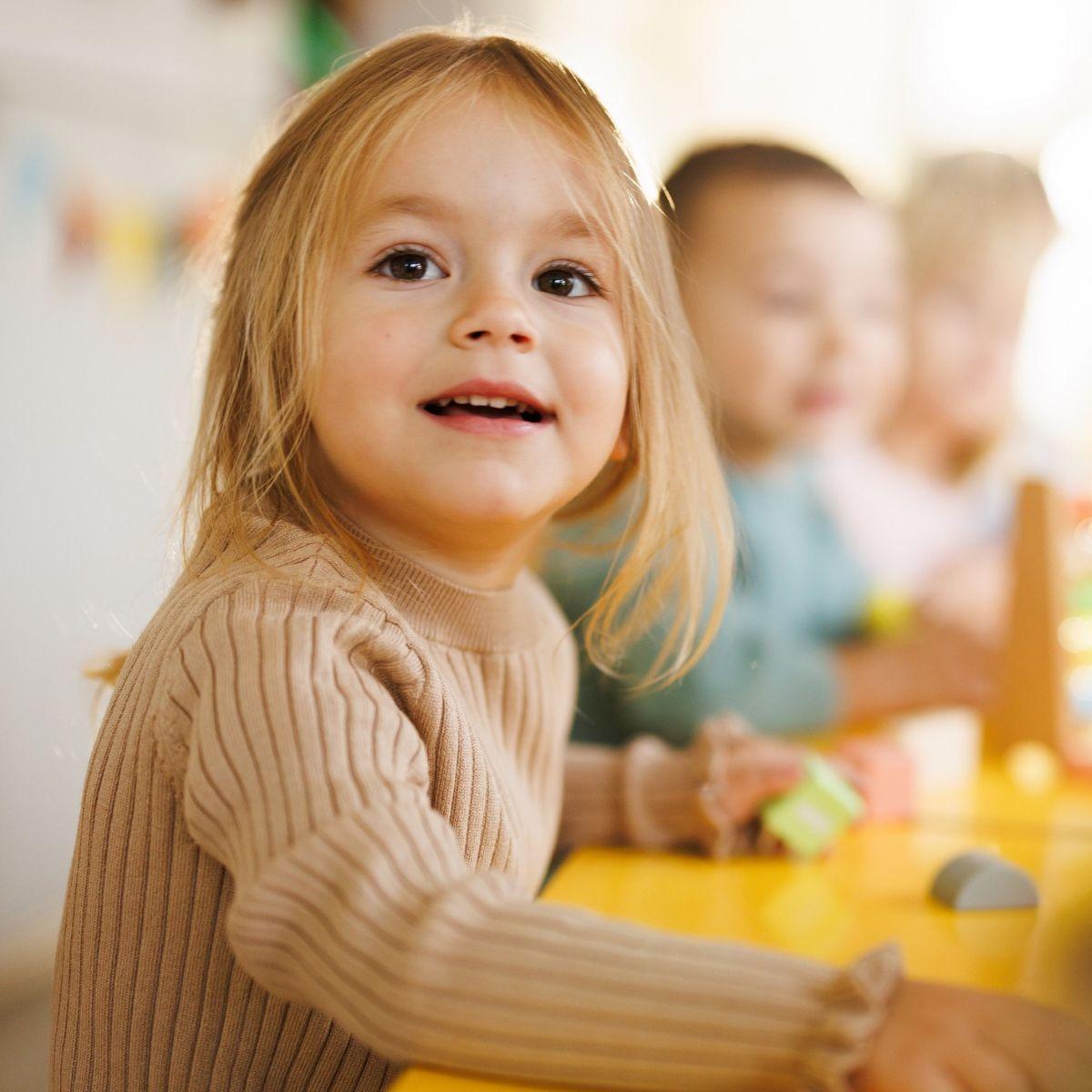 Cute little girl sitting at the table in kindergarten