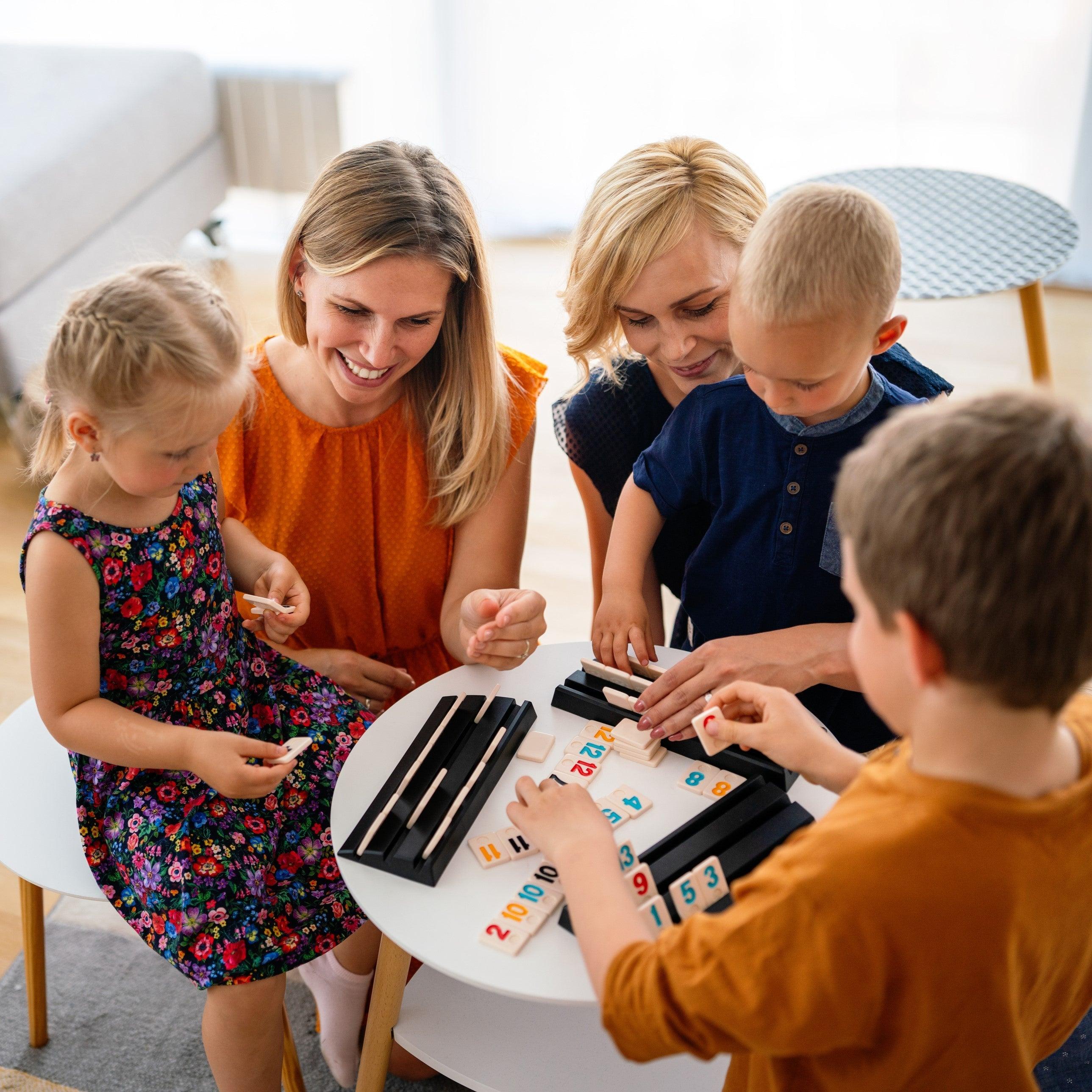 Woman playing board game with children at dining table.