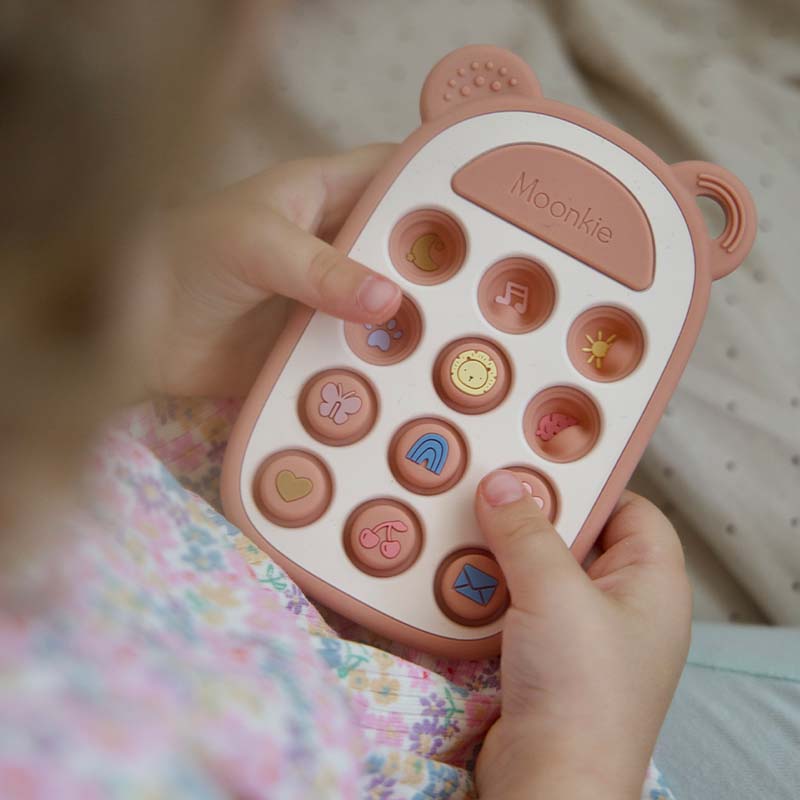 A baby is playing Moonkie's sensory phone toys.