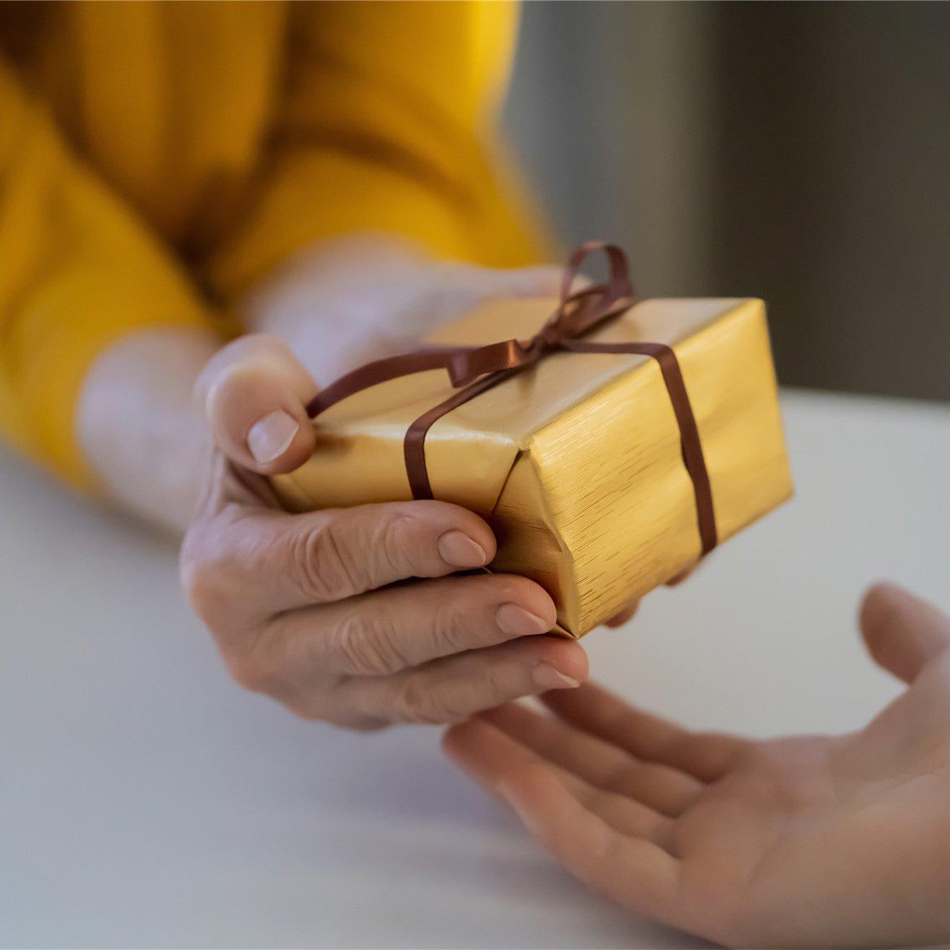 Female hands hold and give a nice packed gift