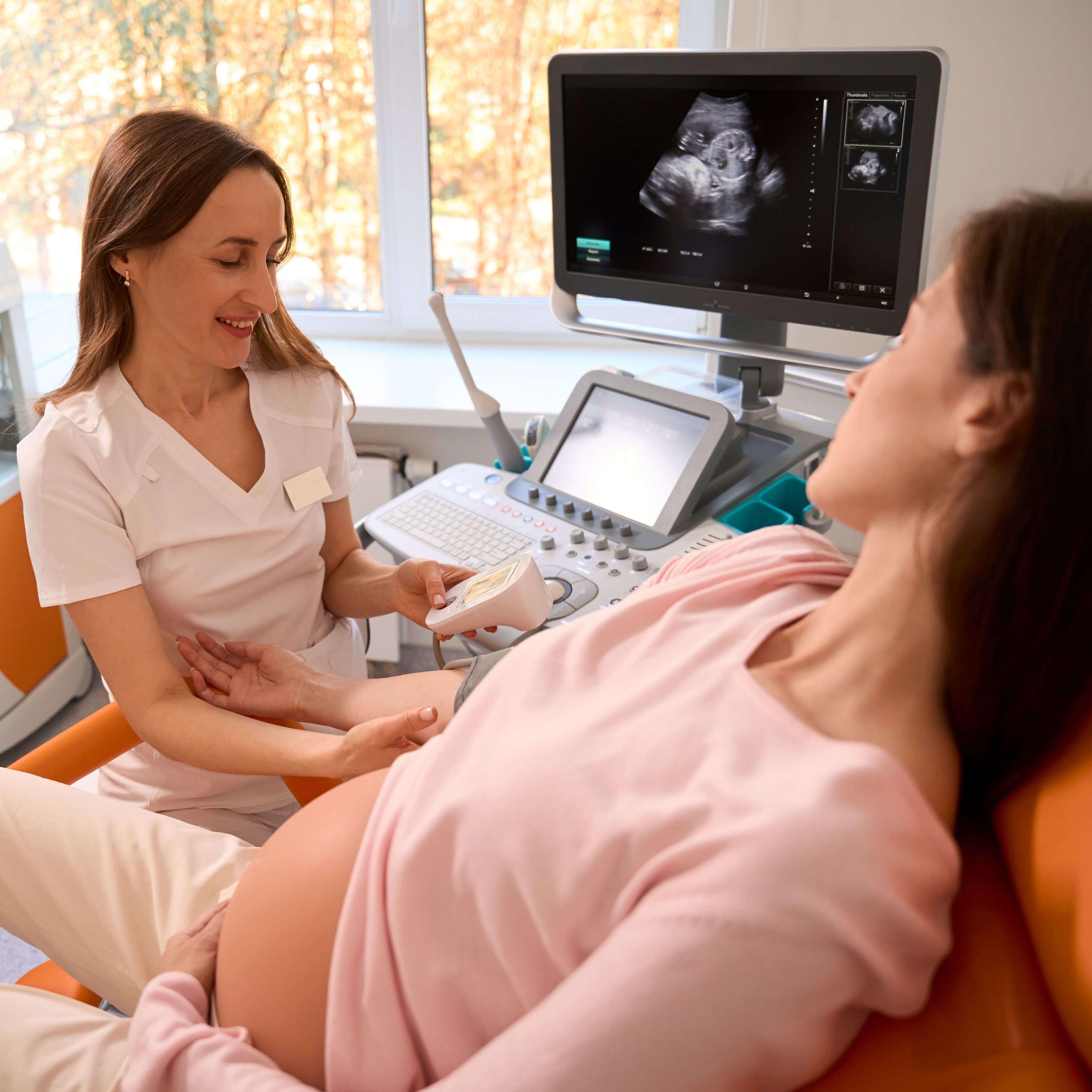 Female nurse performing ultrasound on pregnant woman