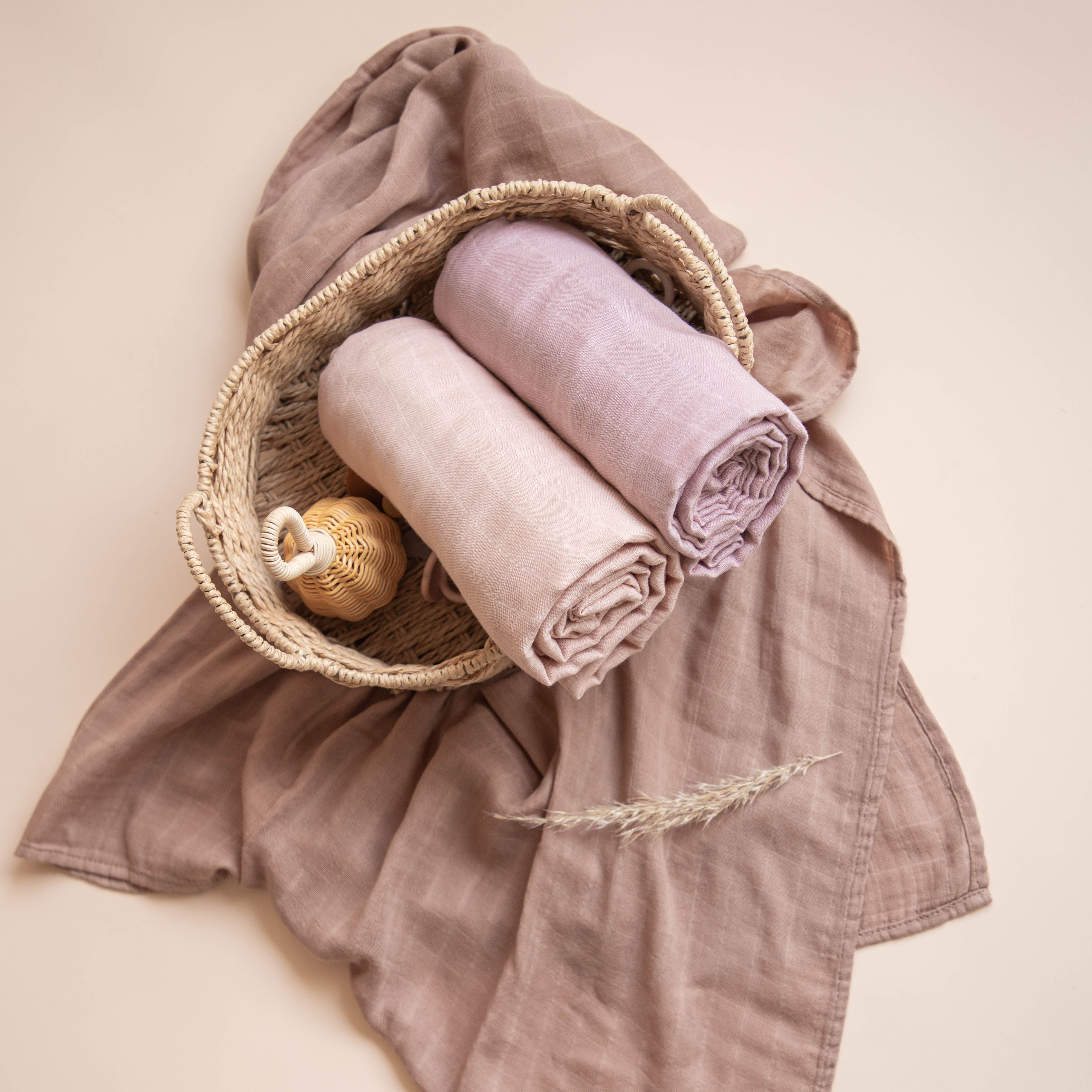 Basket with rolled-up towels and a small bottle on a beige background