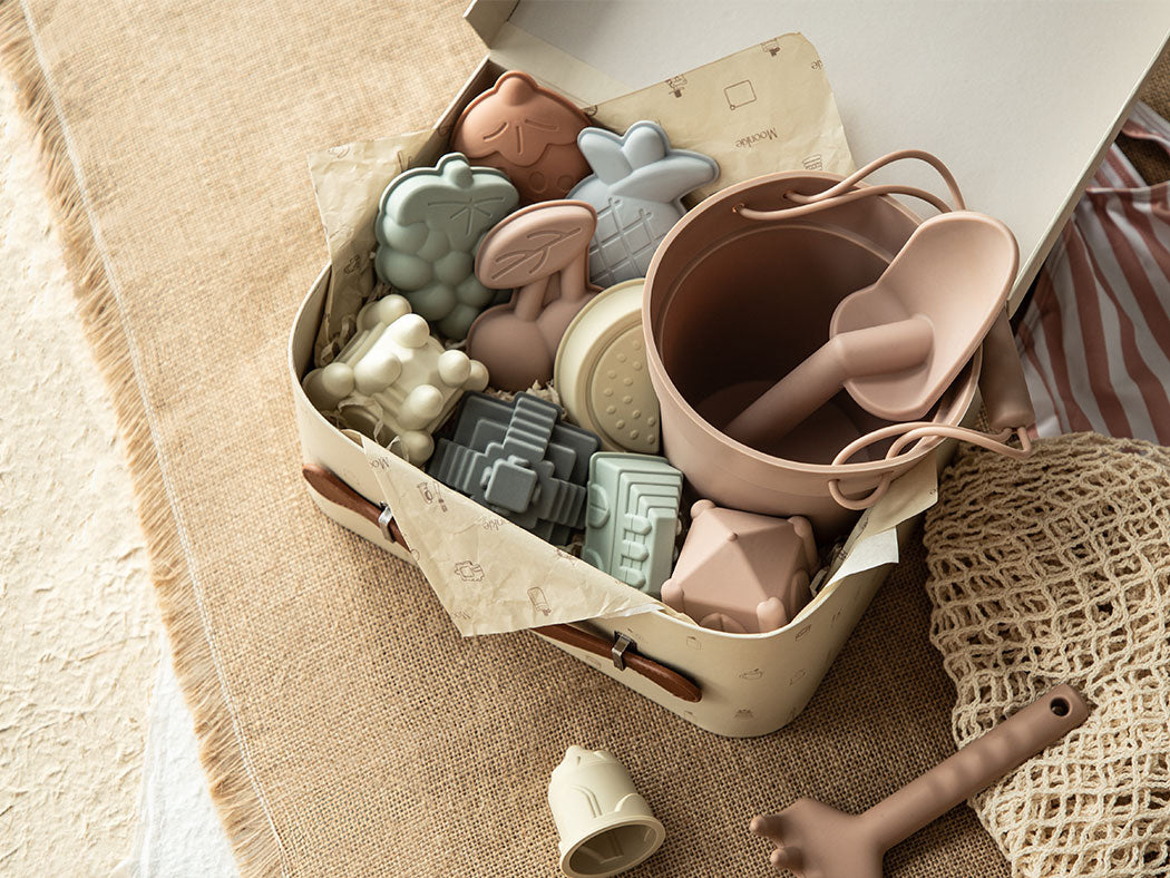 Set of silicone kitchen utensils in a box on a textured surface